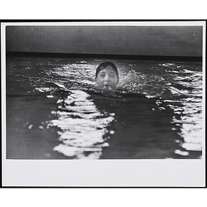 A boy is submerged up to his chin in a natatorium pool