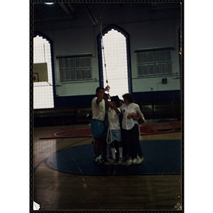 A child and an indoor climbing supervisor hold a climbing rope in a gymnasium