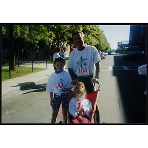 A man poses with two girls at the Battle of Bunker Hill Road Race