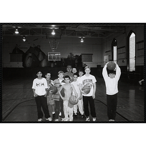 Boys with basketballs pose for a group shot in a gymnasium