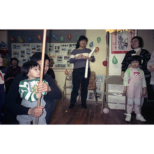 Man crouches to assist a young boy with his swing at a piñata