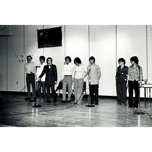 Eight people stand onstage at the Josiah Quincy School in a theatrical sketch about the normalization of U.S. and China relations in the setting of a Chinese restaurant