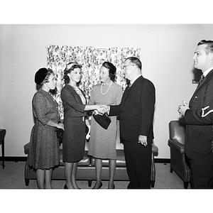 Asa Knowles and Mrs. Knowles shake hands with two female students at a reception for women students