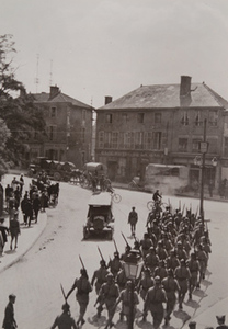 Soldiers carrying bayonets march through a town street