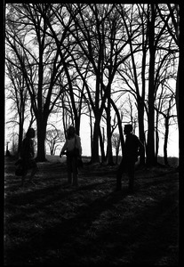 Two women and a man standing in the woods near McGuirk Stadium