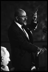 Isaac Deutscher, speaking at the National Teach-in on the Vietnam War: half-length portrait, standing at the podium, gesticulating