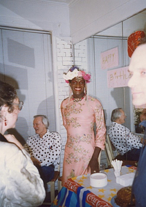 A Photograph of Marsha P. Johnson Posing Standing in Front of a Mirror at Her Birthday Party