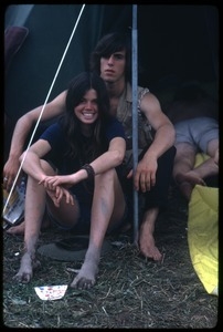 Couple with muddy feet seated in a tent during the Woodstock Festival