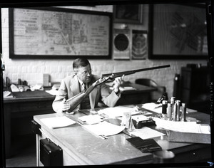 T. J. S. Boake, examining a rifle