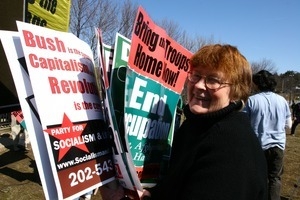 Woman holding signs opposing the Iraq War and promoting Socialism: rally and march against the Iraq War