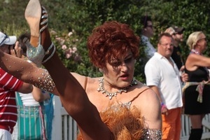 Parade marcher in dress with a furry hem, kicking high : Provincetown Carnival parade