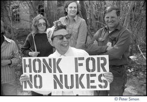 Community protester, an older woman in headscarf and cats-eye sunglasses, holding sign reading 'Honk for no nukes,' Seabrook Nuclear Power Plant