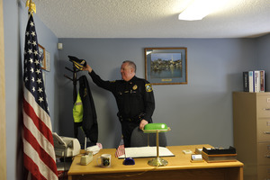 New Salem town police officer arriving at his desk, hanging his hat on a rack