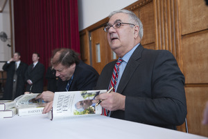 Author Stuart Weisman and Congressman Barney Frank (l. to r.) seated at a table in the Student Union Ballroom stage, UMass Amherst, signing copies of his biography