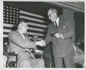 Jeremiah Milbank, Sr. shaking hands with client on stage at Institute Day