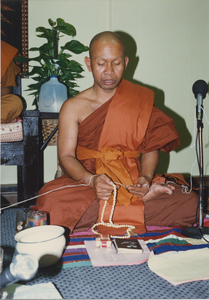 Consecration: Venerable Sao Khon keeps track of the number of times a chant is repeated, 1987