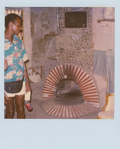 A Photograph of Marsha P. Johnson Wearing a Hawaiian Shirt and Fanny Pack, Standing Near a Brick Fireplace