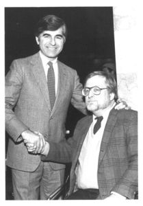 Governor Michael S. Dukakis shakes hands with Suffolk University Professor David Pfeiffer (seated)