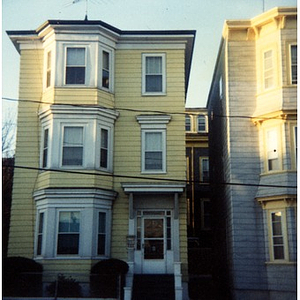 Exterior view of three story yellow house with white trim in Roxbury, Mass