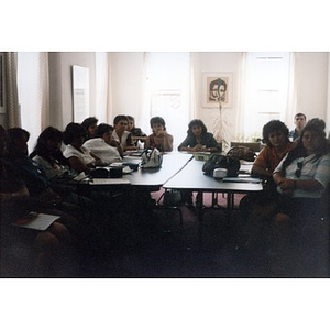 Group of mostly women gathered around tables in the Inquilinos Boricuas en Acción offices for a meeting.