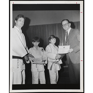 "Black Belt John W. Sullivan presenting Judo promotion to Ralph Cataloni and John Lavery receives the Presidential Physical Fitness Award from Mr. George Wright, Headmaster"