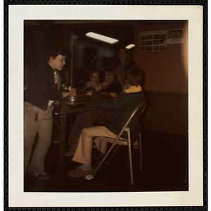 Five South Boston Boys' Club members sit and stand around a table