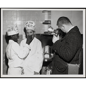 A member of the Tom Pappas Chefs's Club feeds a piece of cake to another member as an unidentified photographer takes their picture