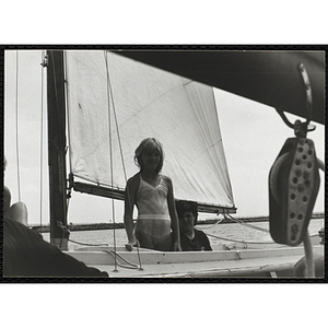 A girl stands on the deck of sailboat in Boston Harbor