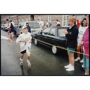 A boy runs in the Battle of Bunker Hill Road Race as spectators look on