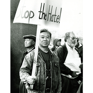 Chinese man holds a sign that reads, "Stop the Hate!" at a rally for immigrant rights and welfare reform