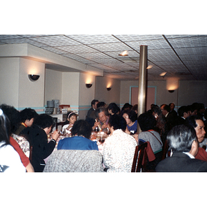 Men, women, and children eat dinner at a Chinese Progressive Association event