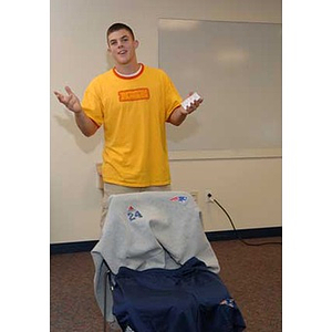 Joseph Bordieri gestures in front of a chair with sweatshirts on it during the Torch Scholars talent show
