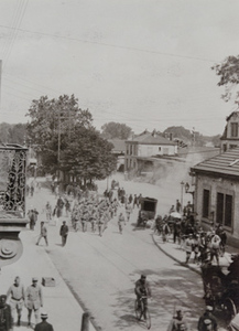 View from above of German prisoners marching through a busy town street, bicycle in foreground