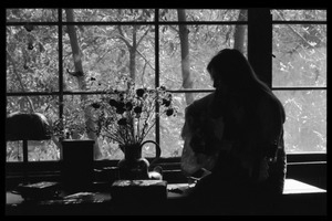 Judy Collins playing guitar while silhouetted against a window in Joni Mitchell's house in Laurel Canyon