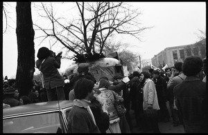 Crowd of demonstrators gathered around a bus painted in psychedelic hues at the Counter-inaugural demonstrations, 1969, against the War in Vietnam