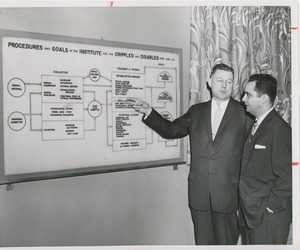 Two men looking at poster laying out ICD's procedures and goals during an administrators' training event