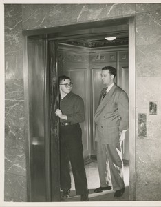 Two unidentified men operating elevator