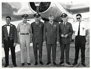 Unidentified group of men standing in front of plane