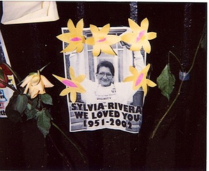 A Photograph of a Poster and Flowers for Sylvia Rivera at Her Memorial Site