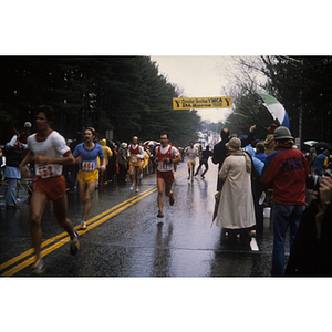 View of runners and crowd on street in the rain at the Boston Athletic Association (BAA) marathon