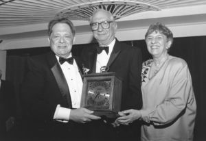 Suffolk University Professor Alexander Cella (Law) receiving a clock from Dean Paul R. Sugarman (Law) and another attendee at a law school event