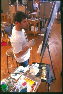 A Suffolk University student paints at an easel during a NESAD painting class