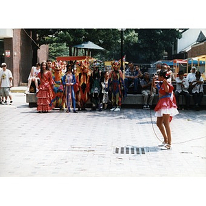 Young girl singing in the plaza at Festival Betances while other young people in costumes look on.