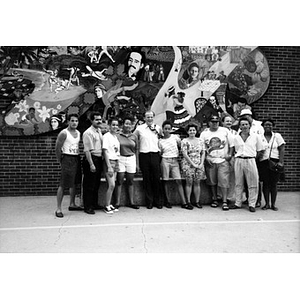 Group portrait of unidentified people standing in front of the "On the Wall" mural.