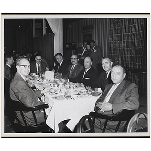 Several men, seated around a table, look at the camera during the Kiwanis Club's Bunker Hill Postage Stamp Luncheon