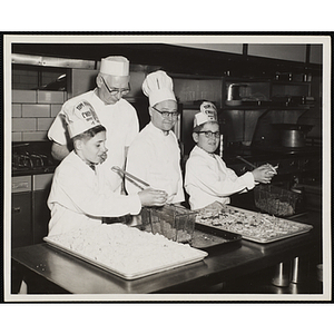 Members of the Tom Pappas Chefs' Club work with a chef and a cook in the Hanscom Field Air Force Base restaurant's kitchen