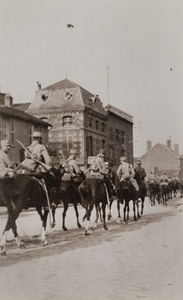 Street-level view of mounted soldiers riding through a town street