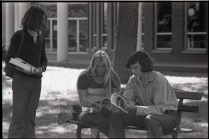 Young couple seated on park bench, reading copy of Free Spirit Press magazine