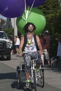 Parade marcher on tricycle, towing large helium balloons : Provincetown Carnival parade