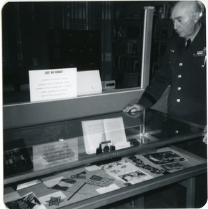 John J. Maginnis looking over his display of World War II memorabilia at the Worcester Public Library